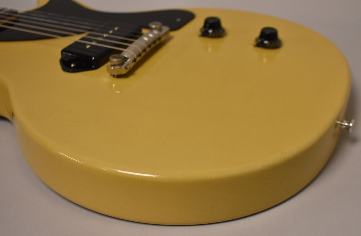 The TV Yellow guitar body, with a black P90 pickup and two black control knobs, shows light finish checking on its lower bout.