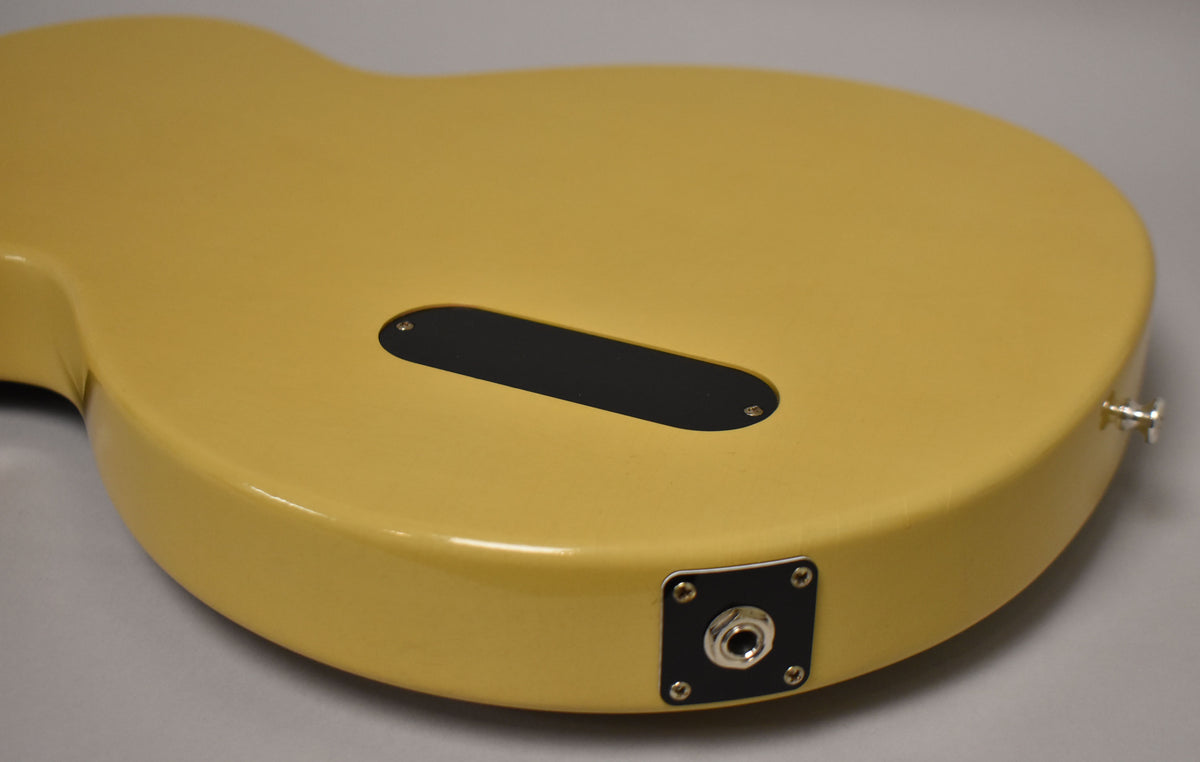 The back of the TV Yellow guitar body, showing the black control cavity cover and the chrome output jack on the lower bout.