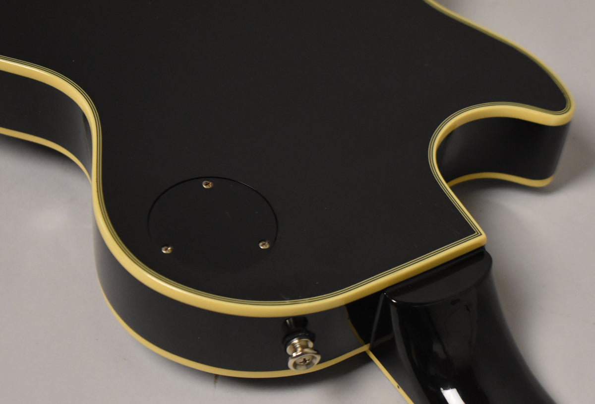 The guitar's black back and side are shown, with cream binding and a circular control cavity cover, plus a strap button.