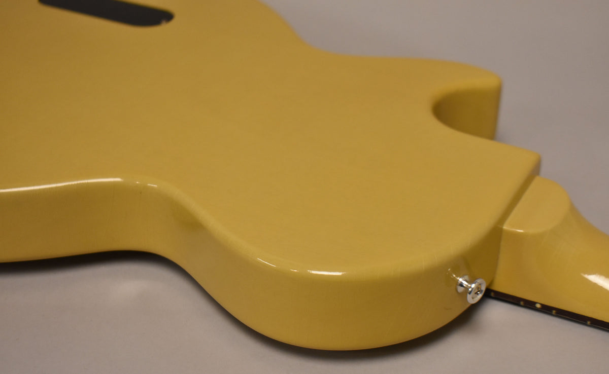 The TV Yellow guitar body, viewed from the back, shows light finish checking and a chrome strap button near the neck joint.