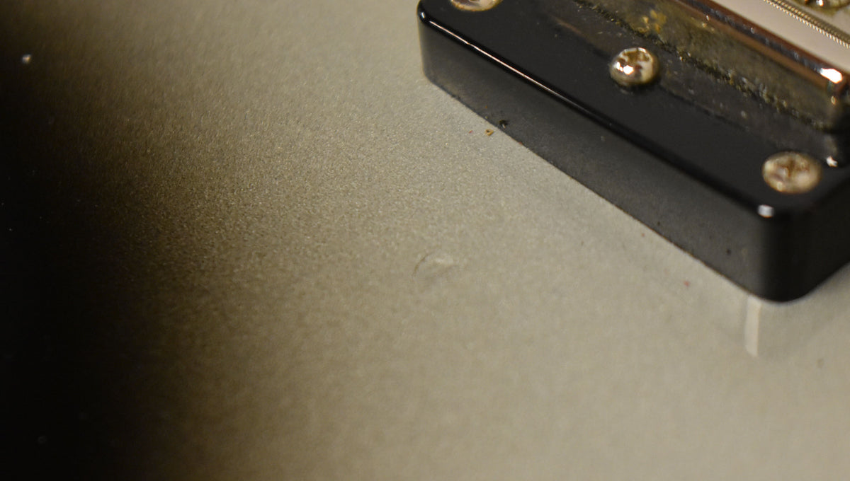 Close-up of the silverburst body, showing a small ding below the black pickup cover with visible mounting screws.