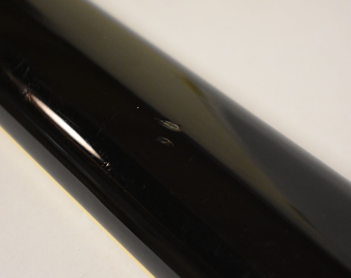 Close-up of the guitar's black gloss body, showing several scratches and two small chips on the finish.