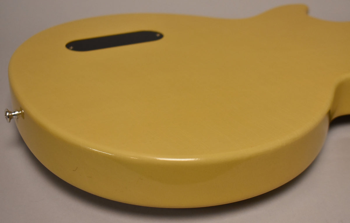 The TV Yellow guitar body's back, angled from the lower bout, shows a black control cavity cover and a chrome strap button.