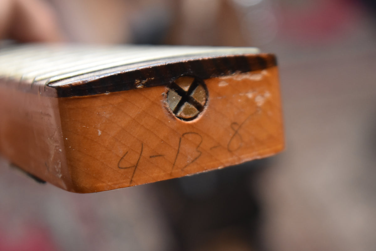 Close-up of the neck heel, showing a cross-head screw, handwritten numbers "4-13-8", and wear on the dark finish edge.