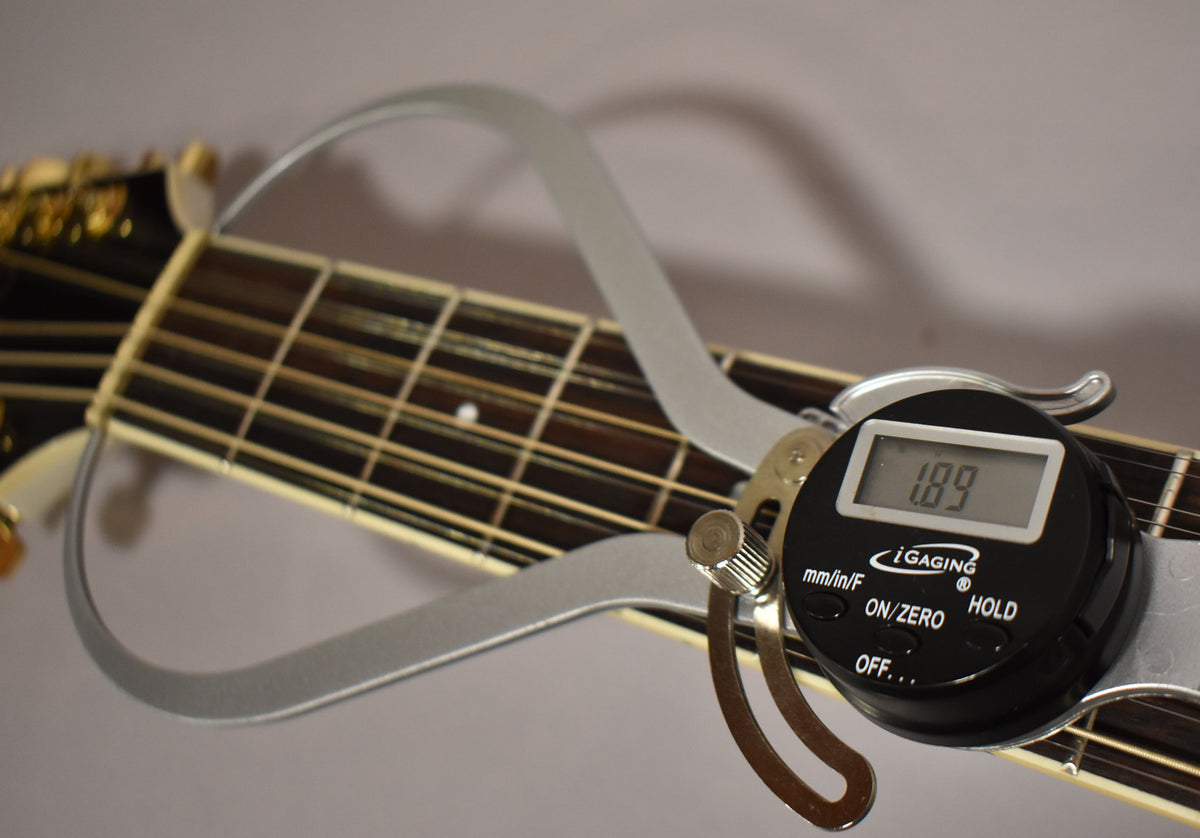 A digital caliper measures the string height at the 12th fret of the 12-string guitar, displaying "1.89" mm/in/F.