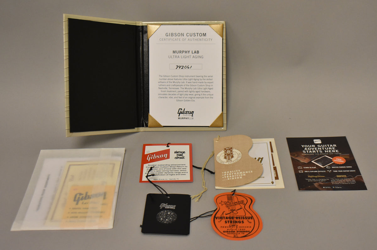 Overhead view of the guitar's case candy, including a certificate of authenticity, hang tags, and various papers.