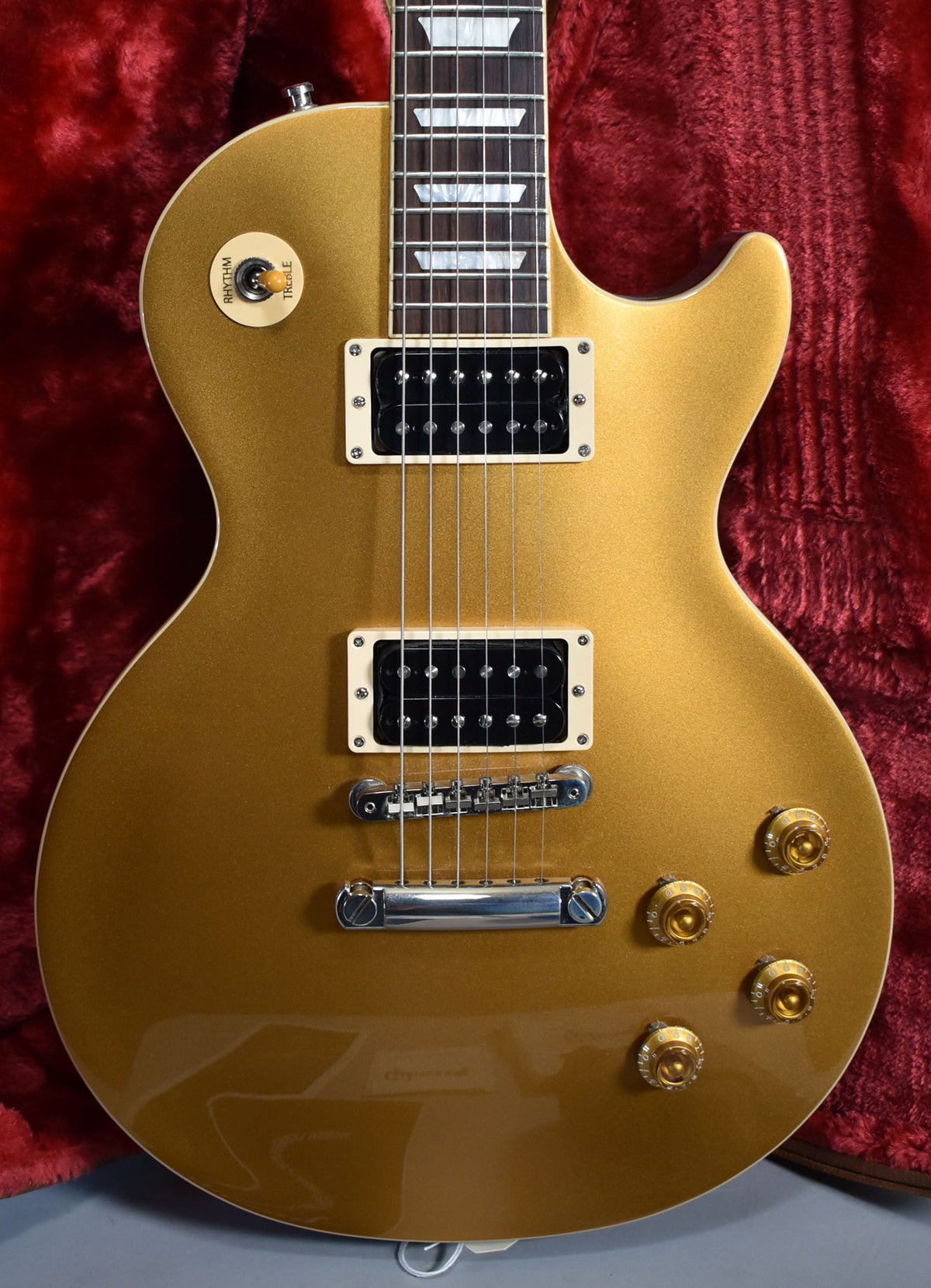 The goldtop Les Paul's body and lower neck are framed, showing cream binding, humbuckers, and gold speed knobs.