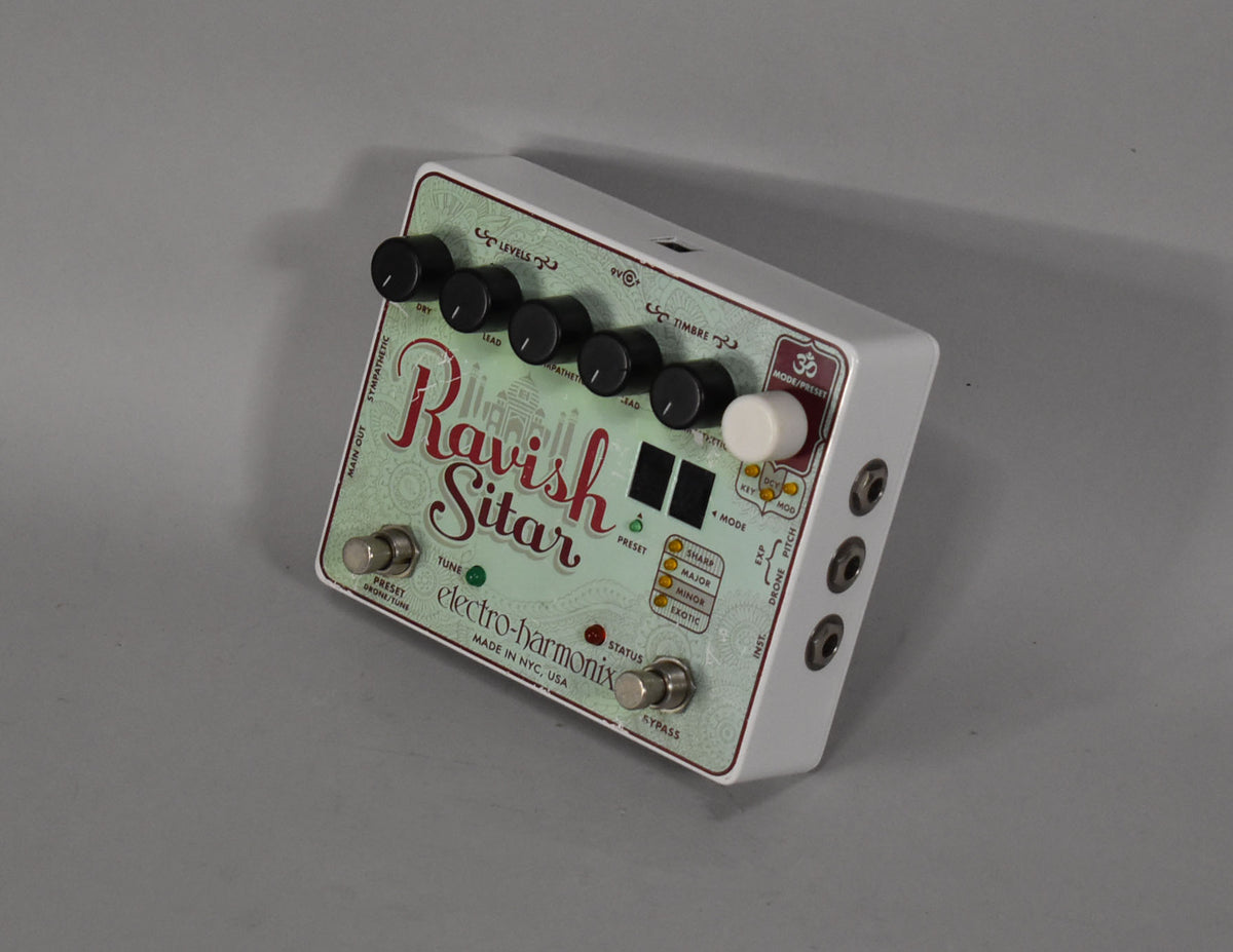 A white guitar pedal with a light green faceplate, black knobs, and a large white knob, viewed from the front-right.