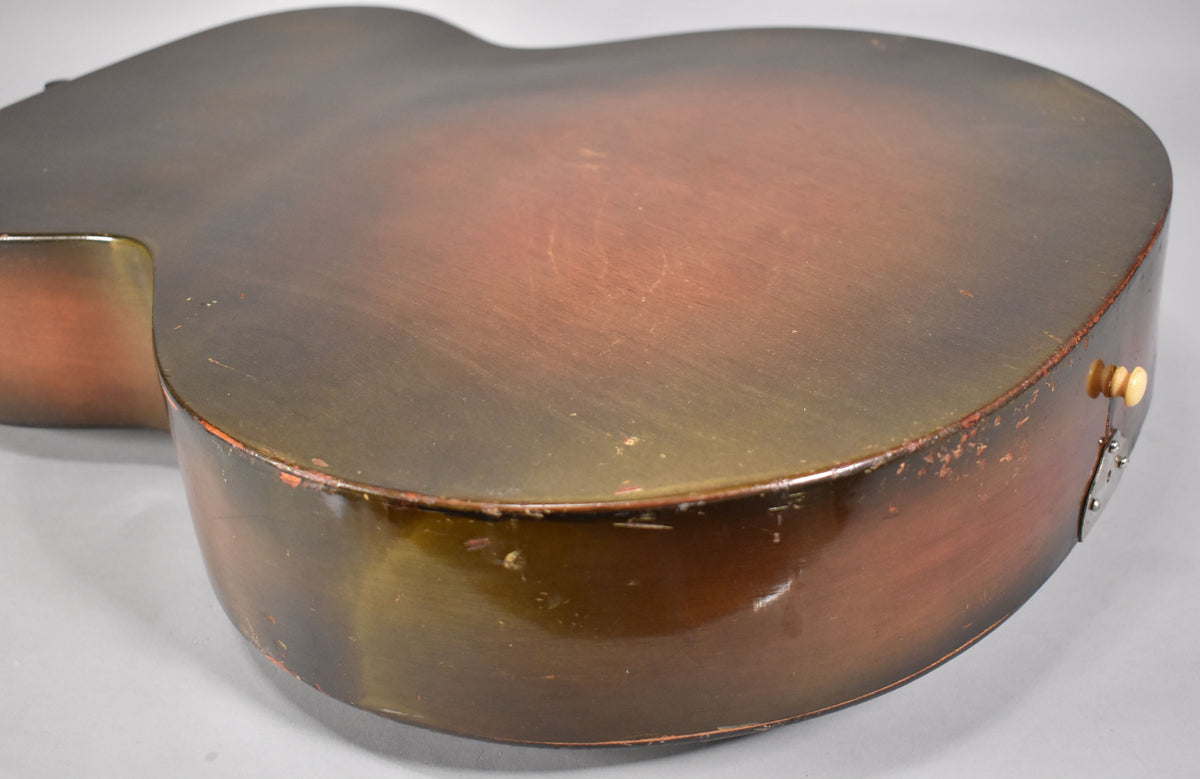 The lower bout of a sunburst archtop guitar, showing heavy finish wear and checking on the sides and back.