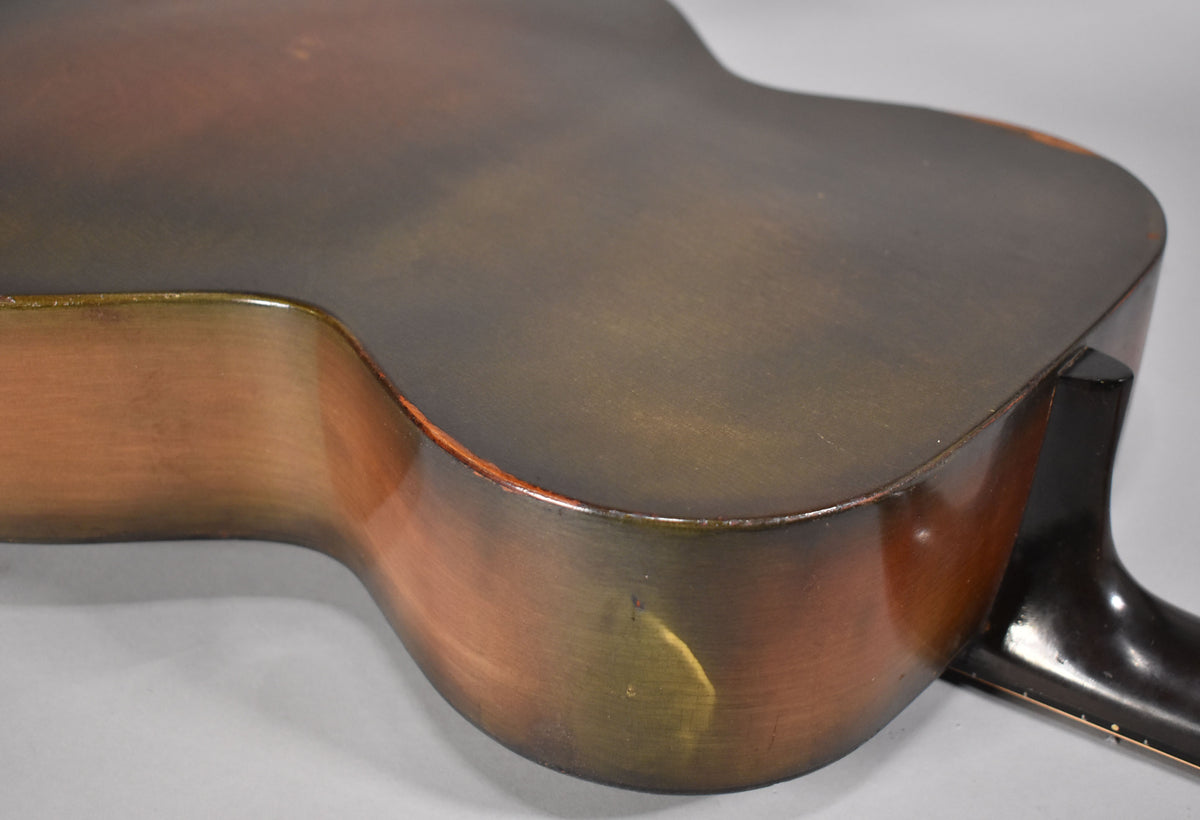 The lower bout of a vintage sunburst archtop guitar, showing wear and finish checking on the dark brown top and lighter brown sides.