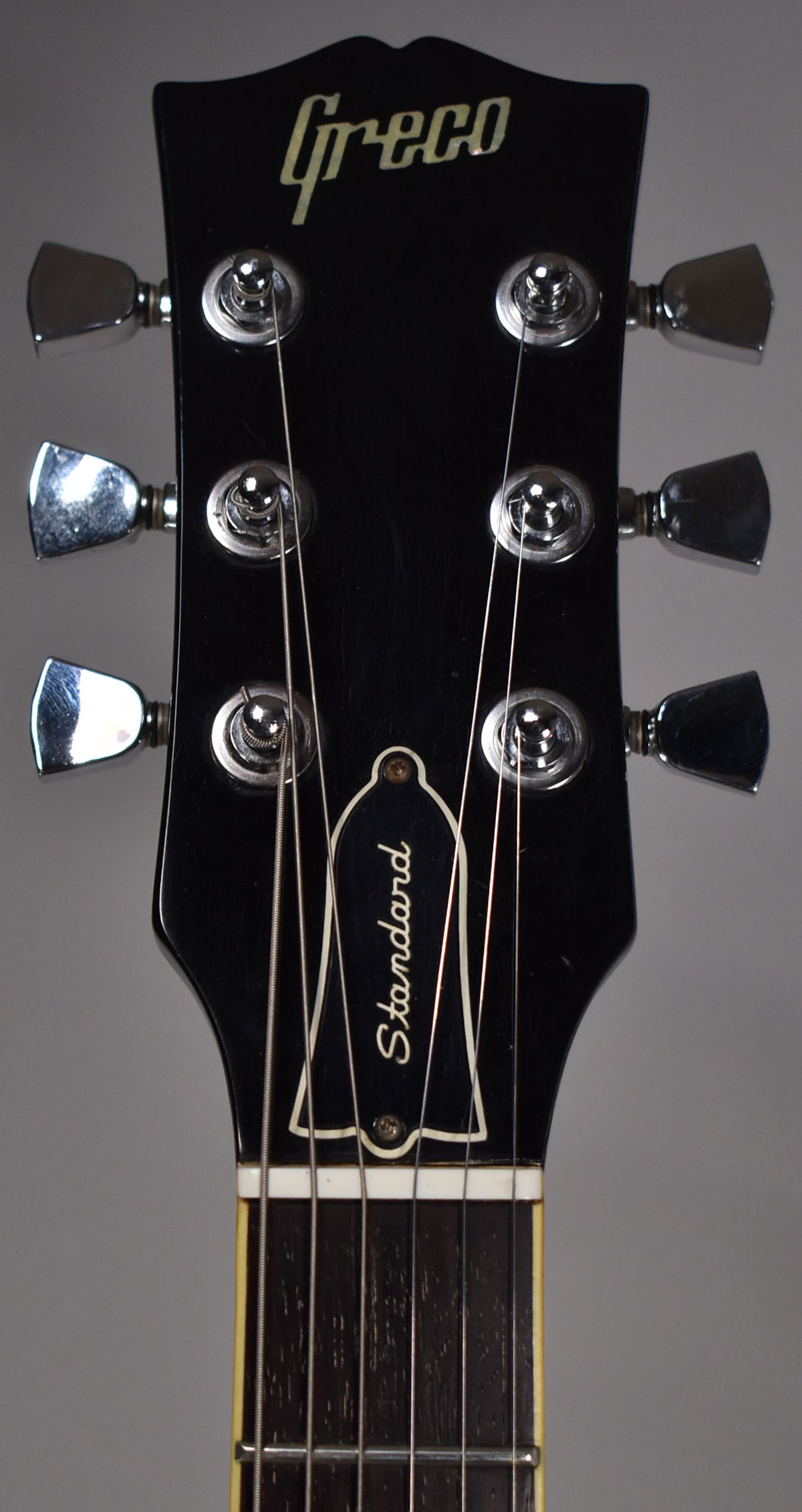 The black headstock, with chrome tuners and a white "Standard" bell-shaped truss rod cover, shows light wear and fine scratches.