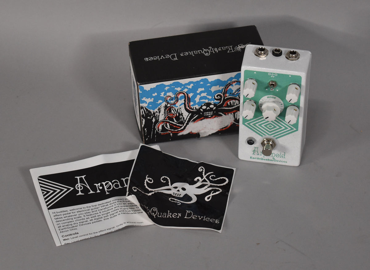 A white pedal with a teal faceplate, six white knobs, a footswitch, and three jacks, shown with its box and papers.