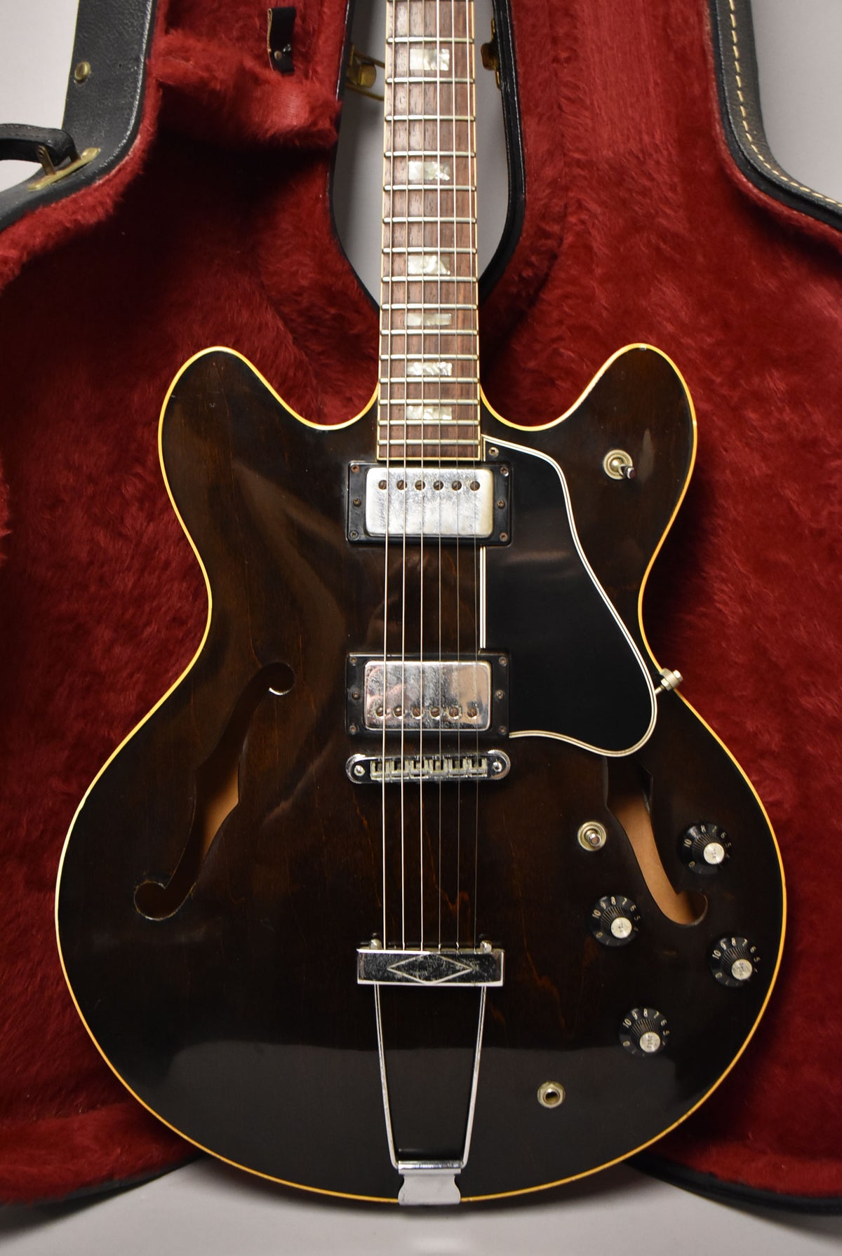 Full-frame view of a dark walnut ES-335TD, showing its body, neck, and headstock in a red-lined case.