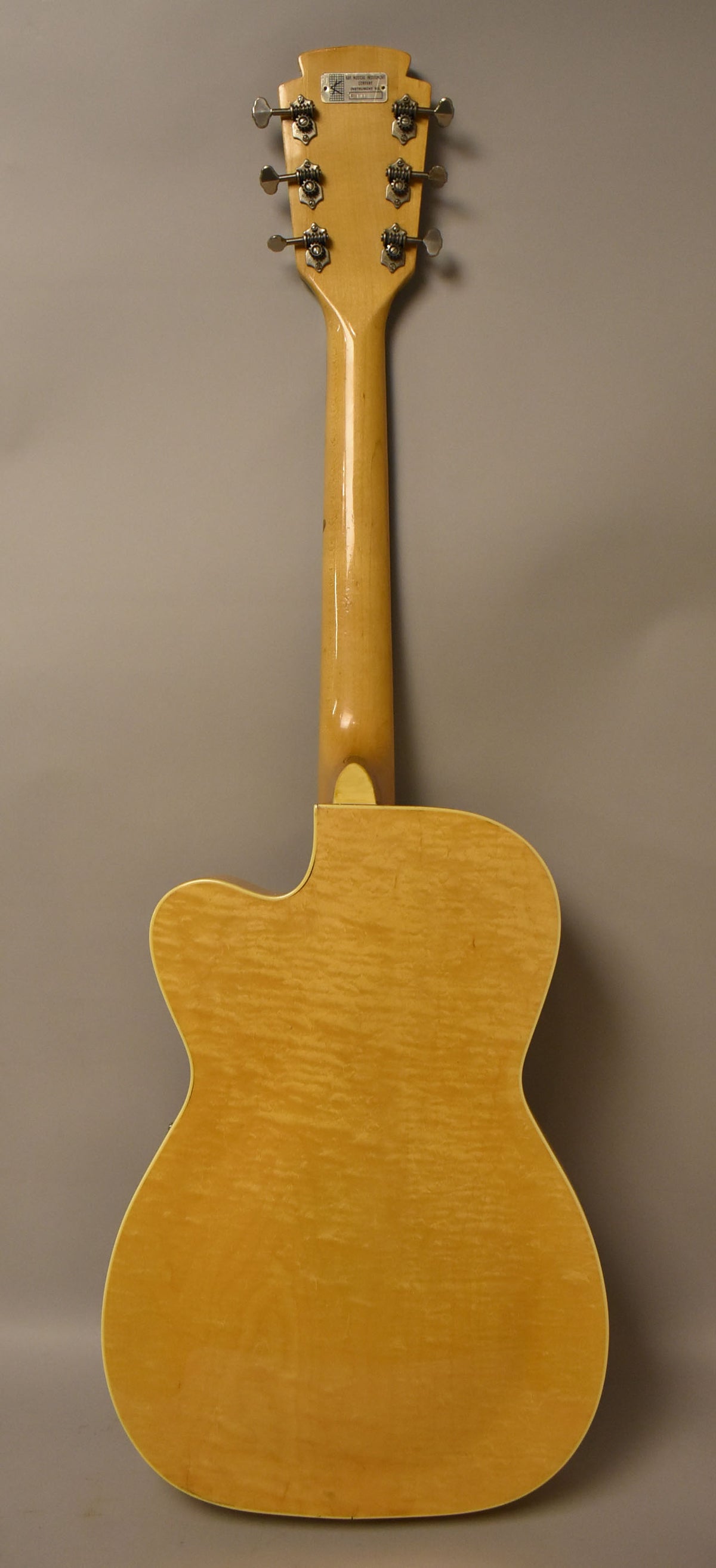 The full back of the natural finish archtop guitar, showing its figured maple body, neck, and headstock with six chrome tuners.