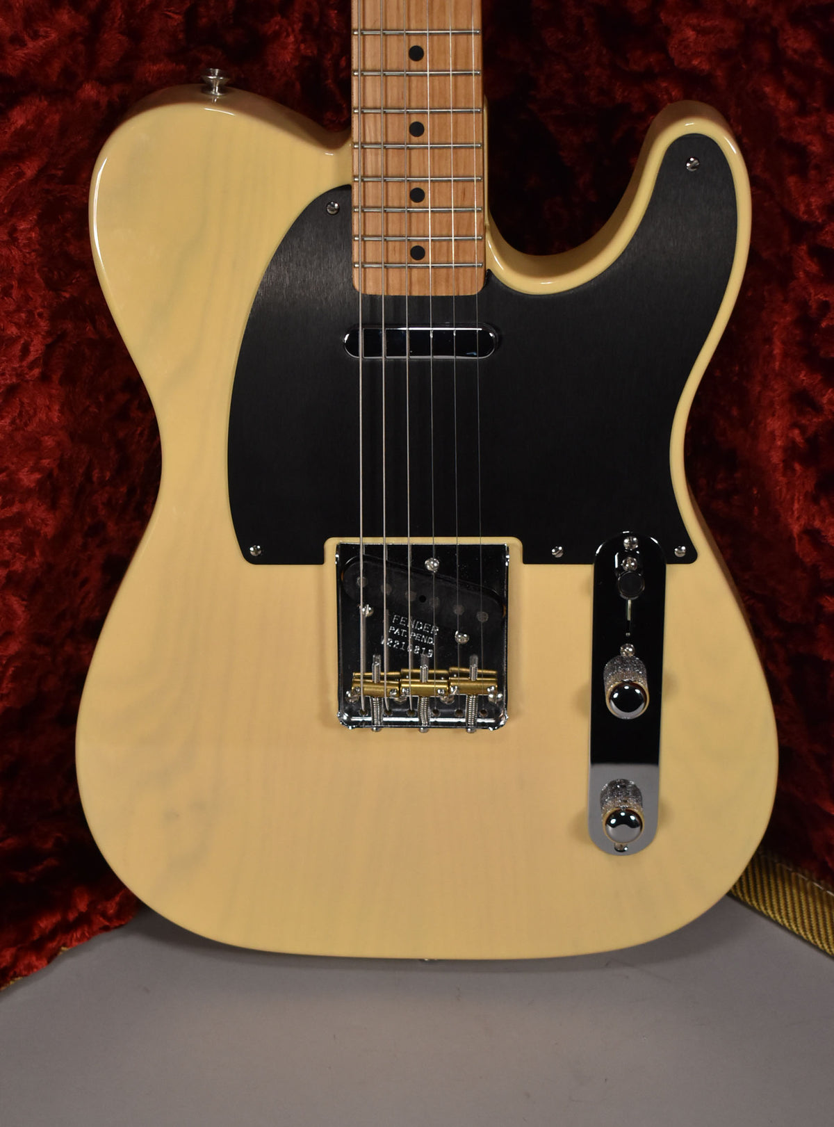Full-frame view of a blonde Telecaster with a black pickguard, maple fretboard, chrome bridge with brass saddles, and two chrome knobs.