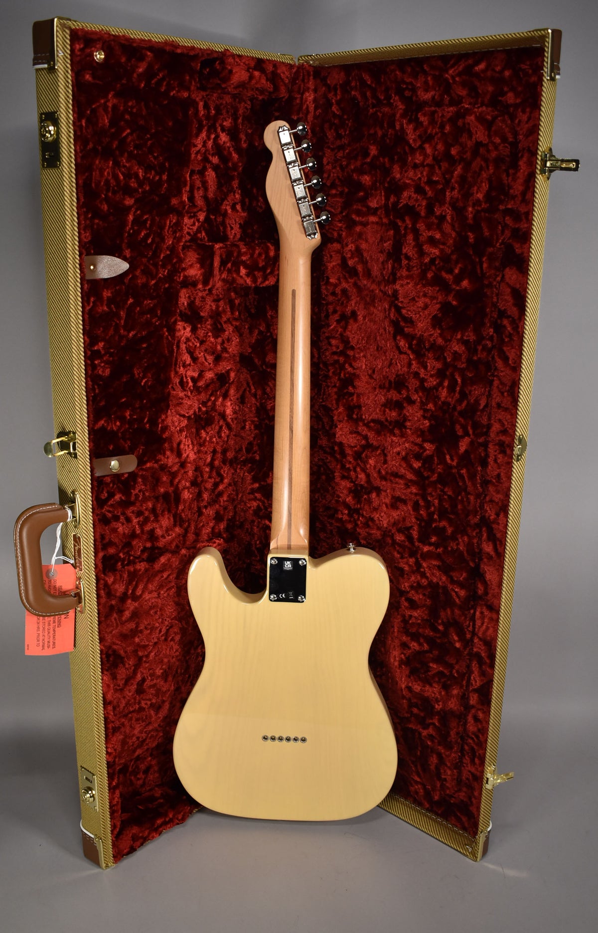 The blonde Telecaster is shown from the back, resting in a tweed hard case with red crushed velvet lining.