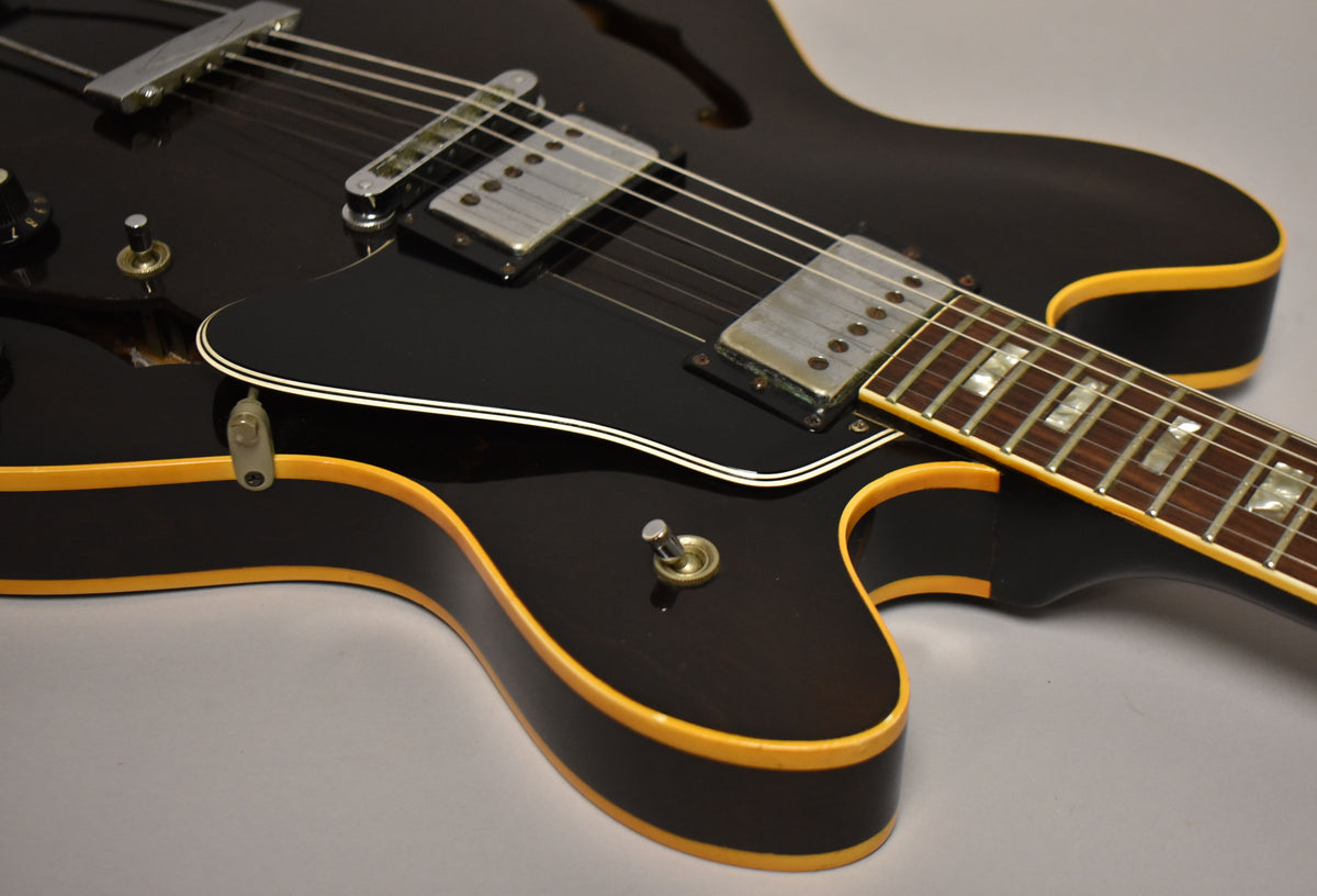 Close-up of the dark walnut body, showing the bridge pickup, pickguard, and lower bout with a few light scratches.