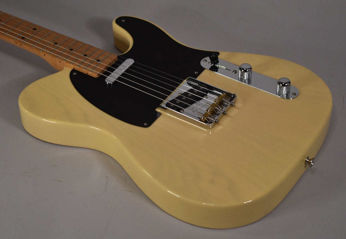 A blonde Telecaster body with a black pickguard, chrome bridge, control plate, and neck pickup, angled from the lower bout.
