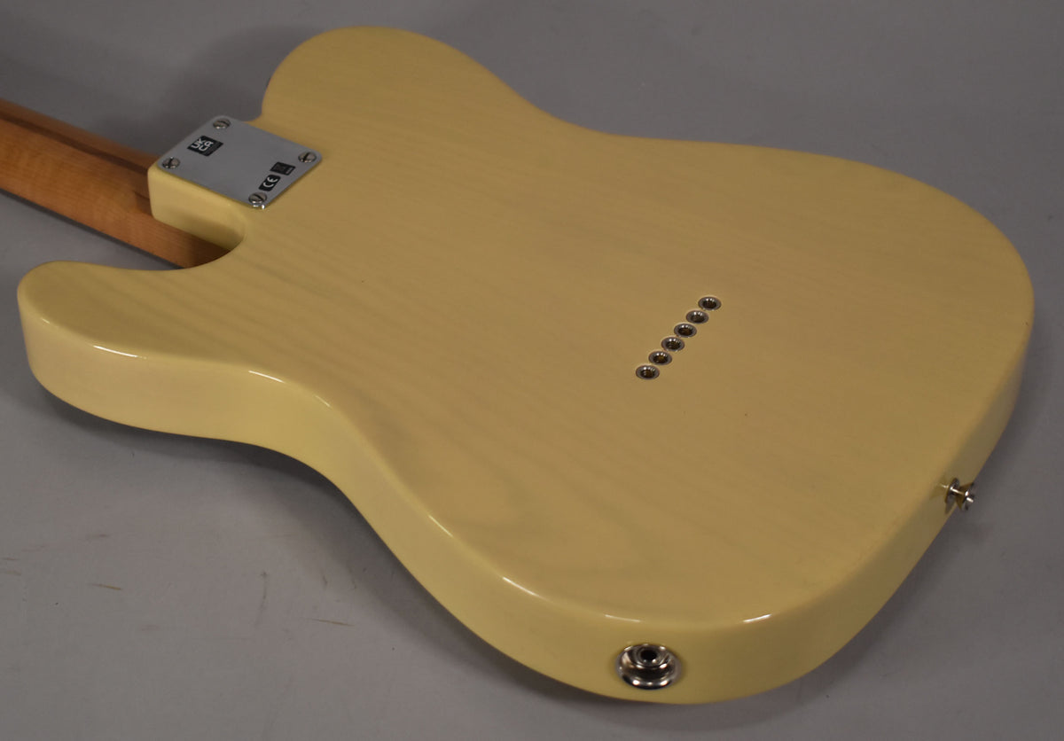 The back of a blonde Telecaster body, showing the neck plate, six string-through-body ferrules, and output jack.