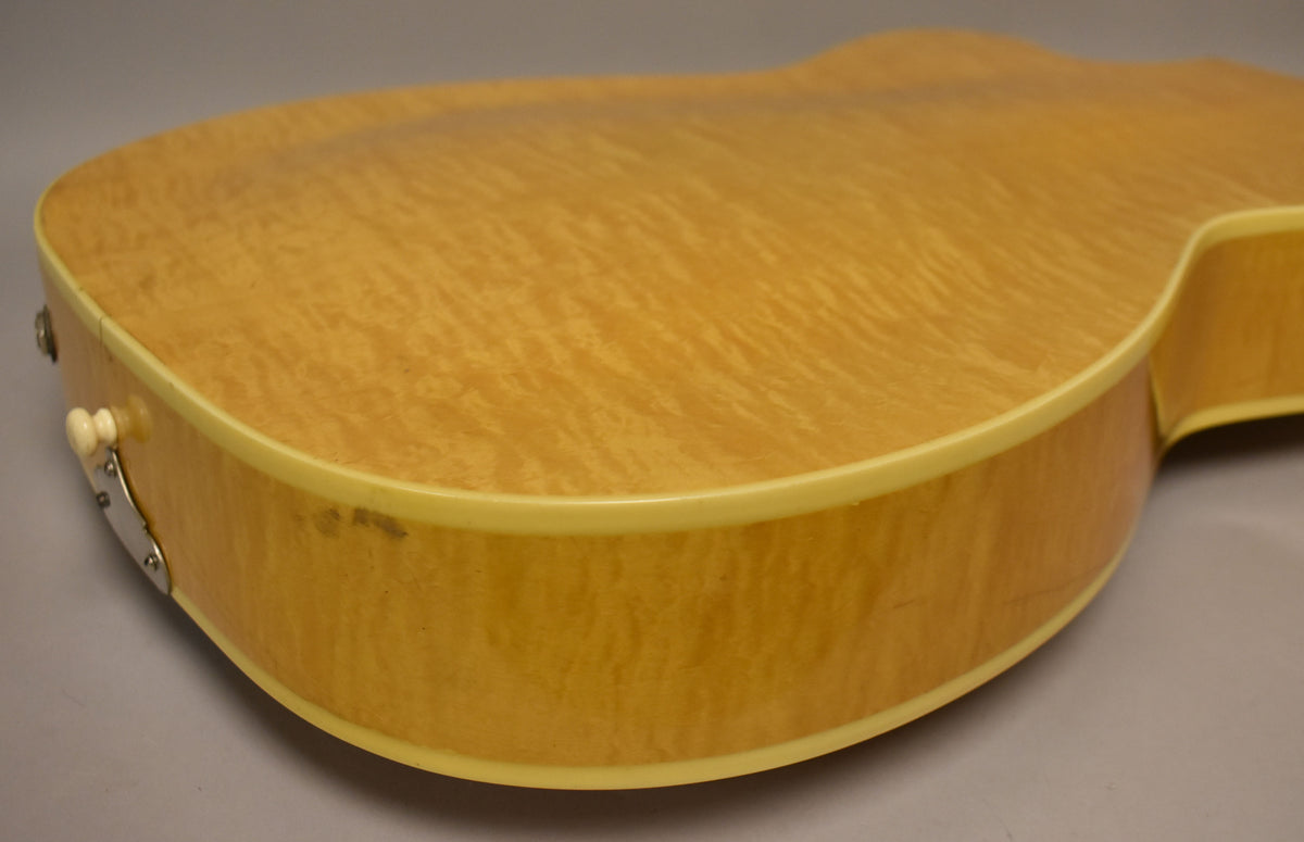 Close-up of the lower bout, showing the natural finish with flame maple grain, cream binding, and a small output jack.