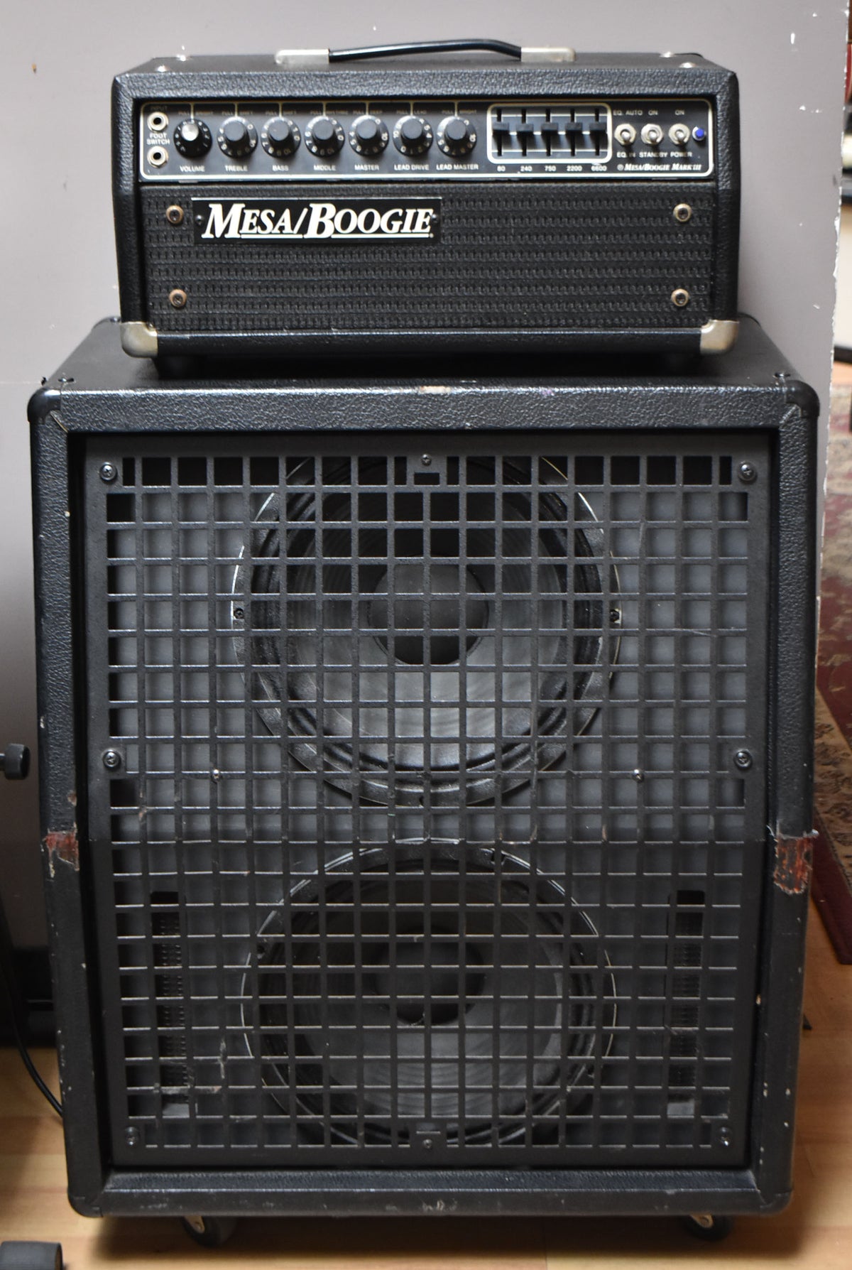 Full front view of a black textured amplifier head with chrome corners, stacked on a matching 2x12" cabinet with a metal grid.