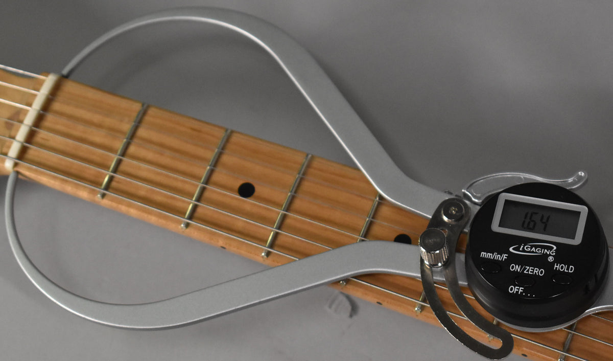 Close-up of the guitar's roasted maple fretboard with a digital fret rocker showing a reading of 1.64.