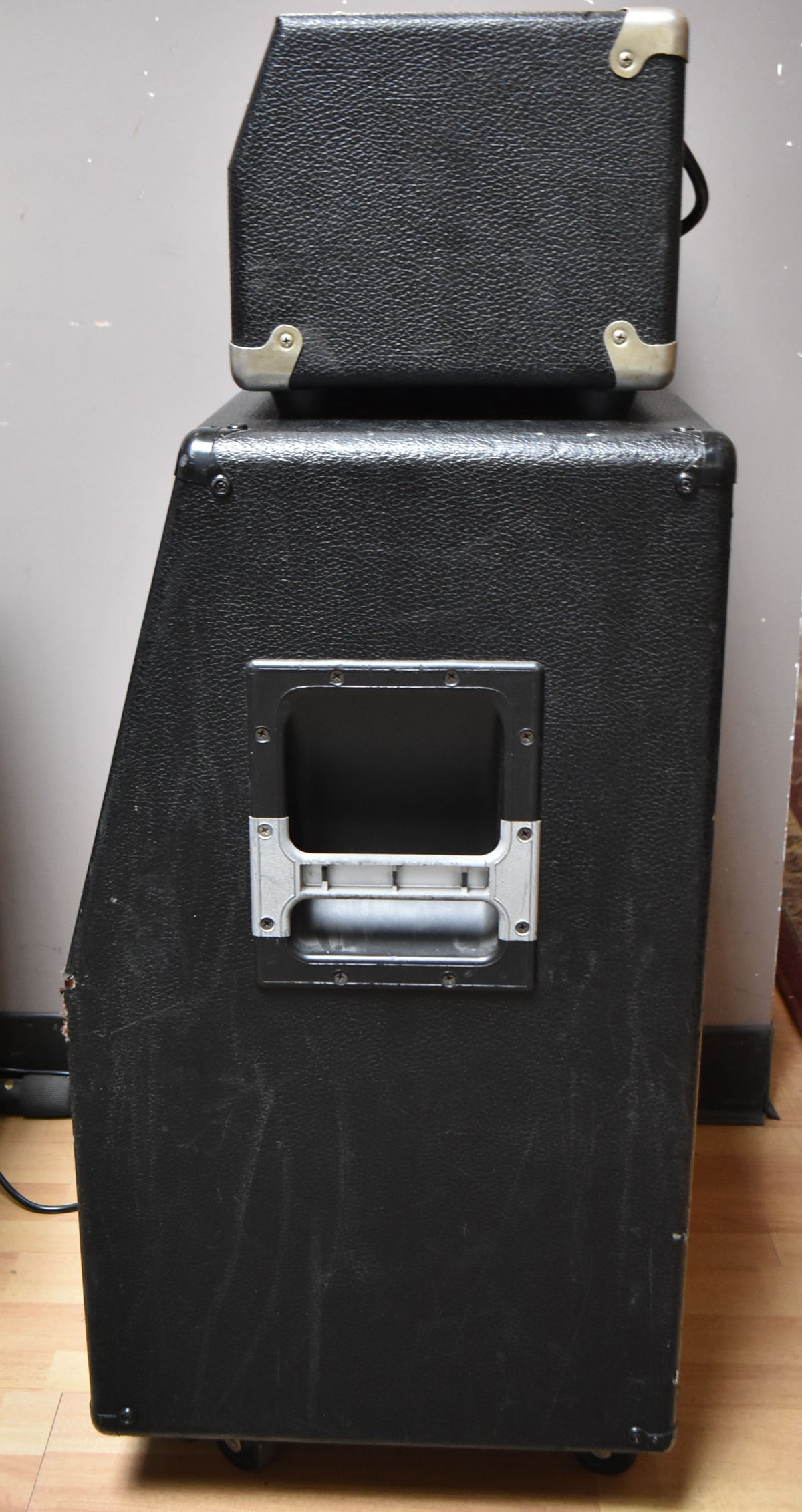 Side view of the black textured amp head and cabinet, showing a recessed handle on the cabinet and metal corner protectors.