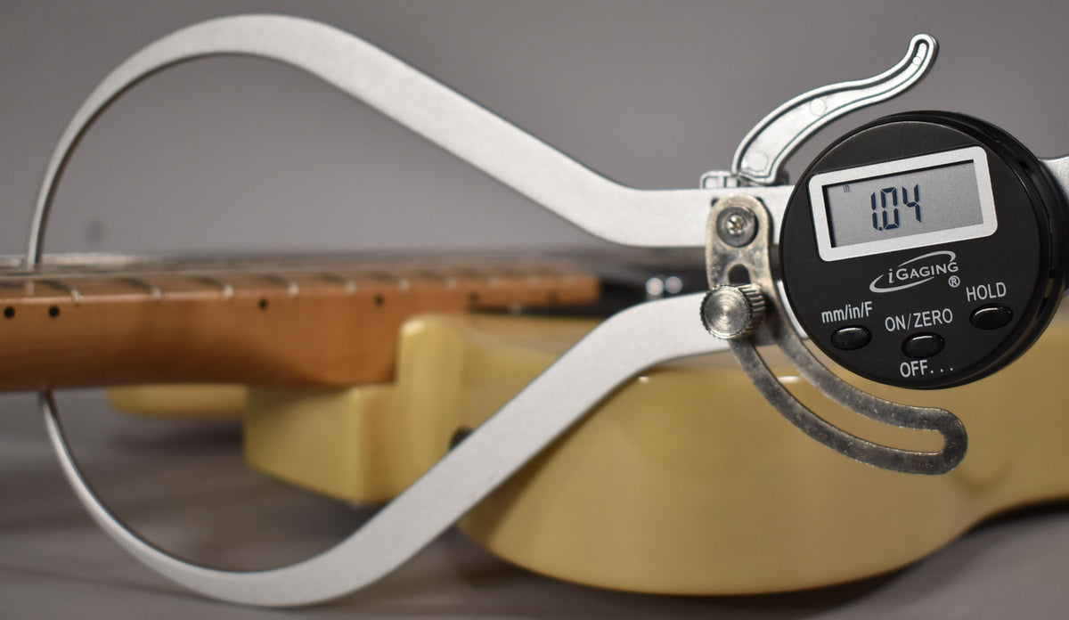 A digital caliper measures the neck thickness of the blonde Telecaster at 1.04 inches, showing the fretboard and body.