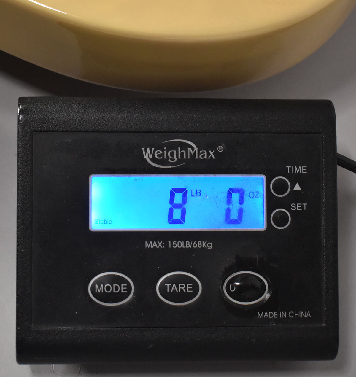 The blonde guitar body rests on a black digital scale displaying "8 LB. 0 OZ." on a bright blue screen.