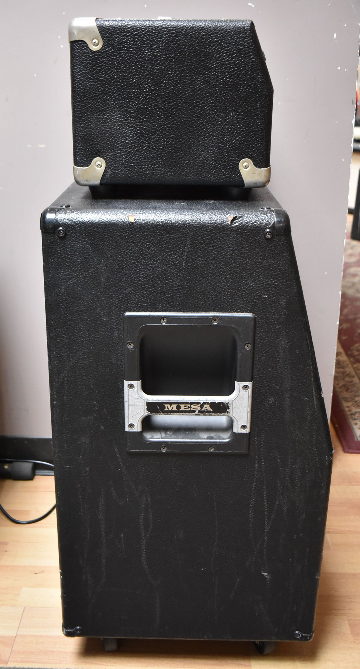 A full-height view of the black textured amp head and cabinet, showing the cabinet's side handle and scuffs on the tolex.