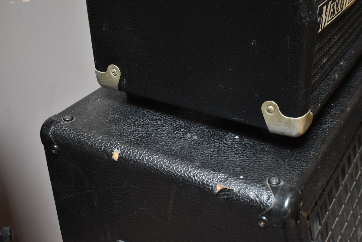 Close-up of the black textured amplifier head stacked on the matching cabinet, showing scuffs and tears on the tolex.