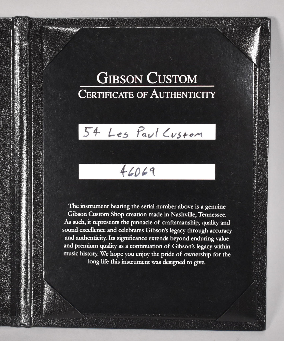 A black textured folder holds a Gibson Custom Certificate of Authenticity, with "54 Les Paul Custom" handwritten on it.
