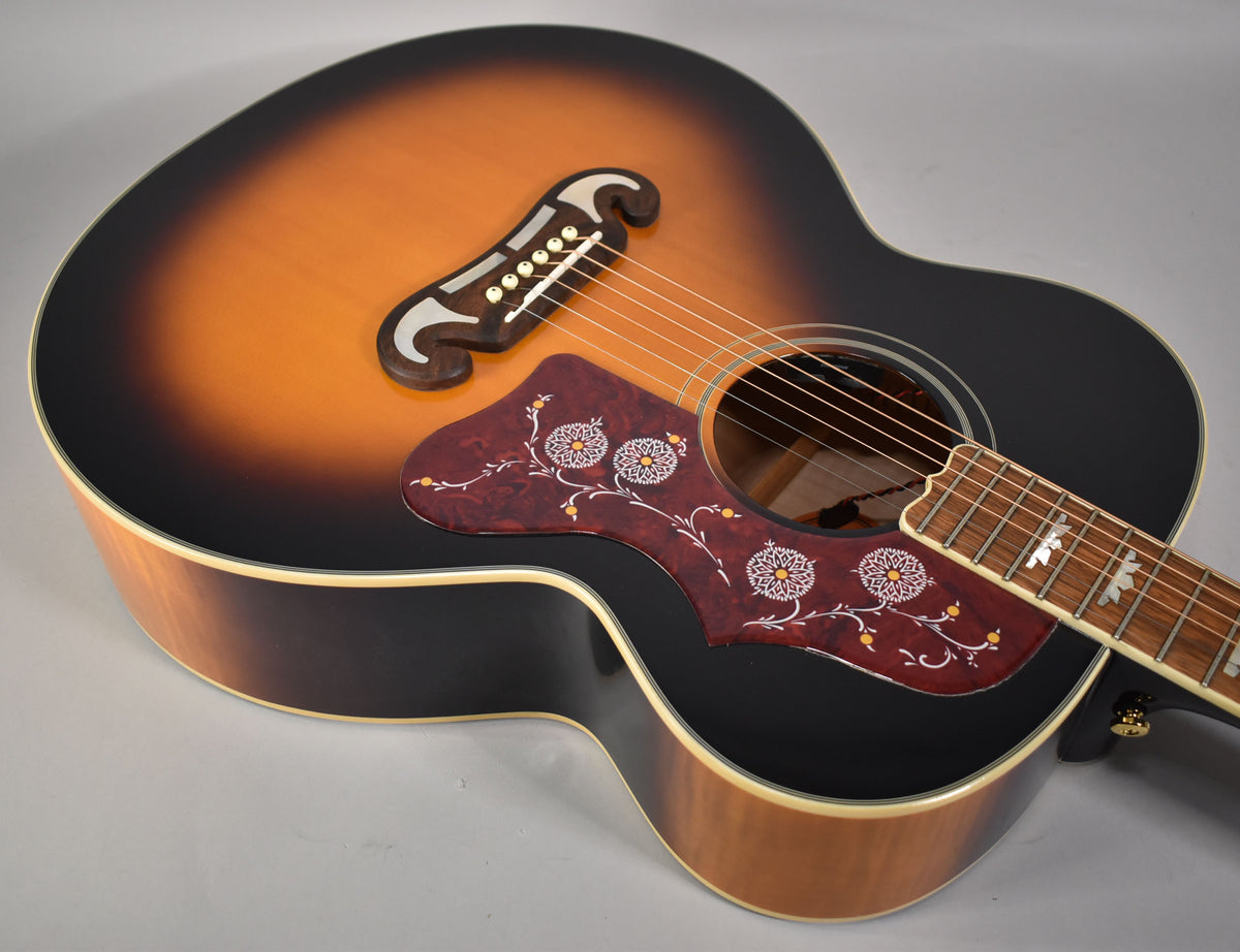 Overhead view of the sunburst guitar body, showing the ornate pickguard, bridge, soundhole, and part of the fretboard.