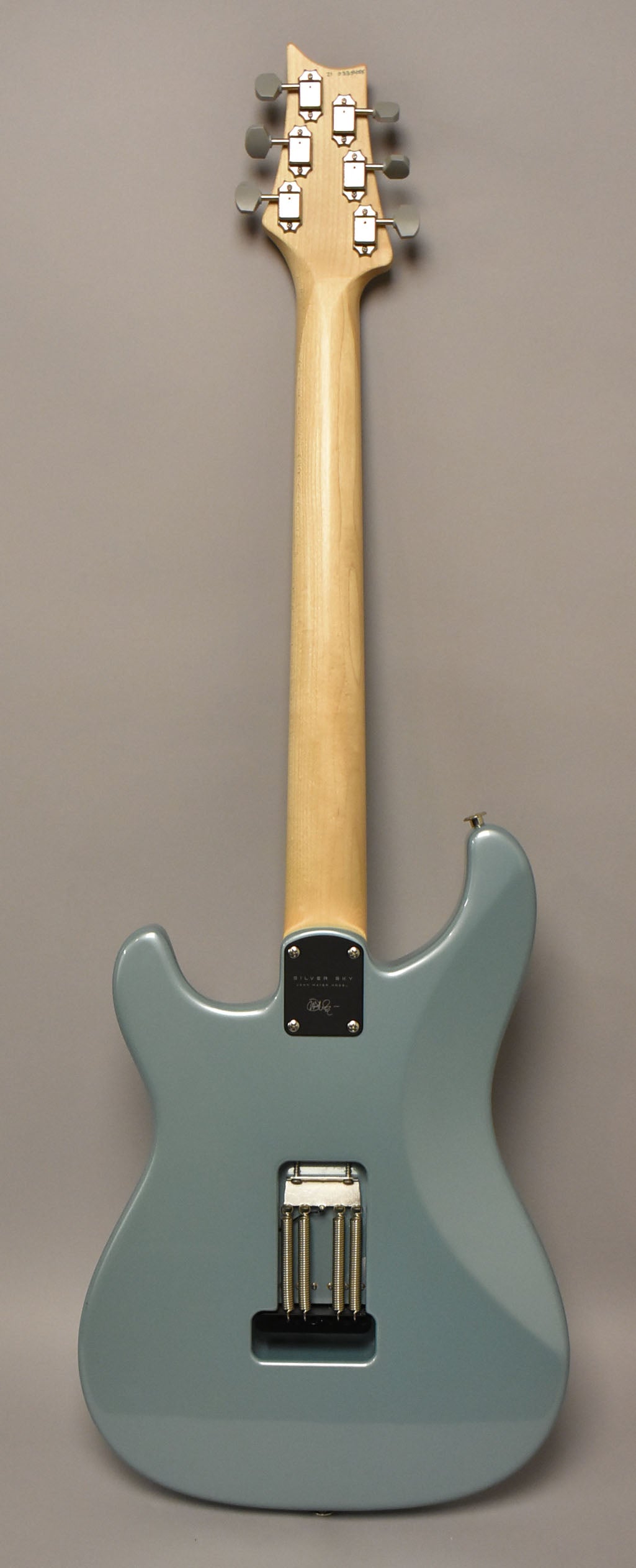 The guitar's back is shown, featuring a light blue body, a natural maple neck, and a chrome tremolo spring cavity.