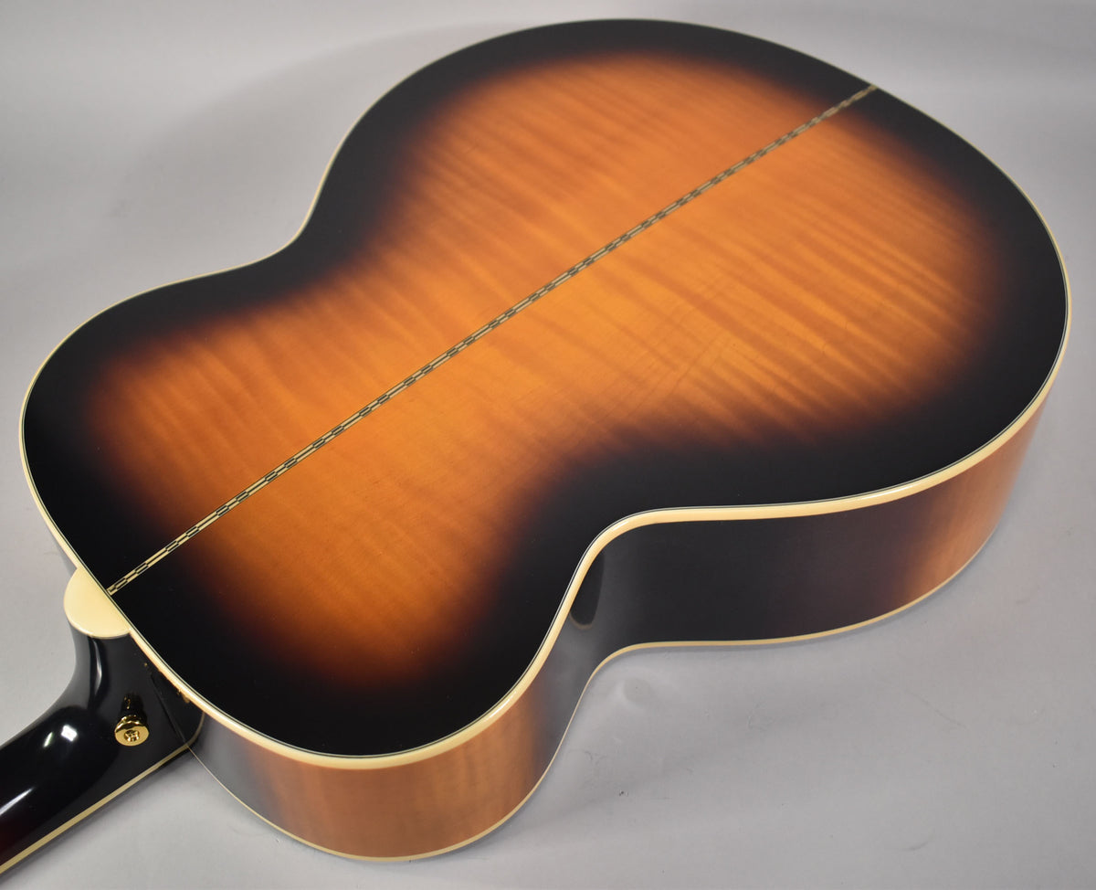 The guitar's back, in aged vintage sunburst gloss, shows a center seam and flame maple grain, with cream binding.