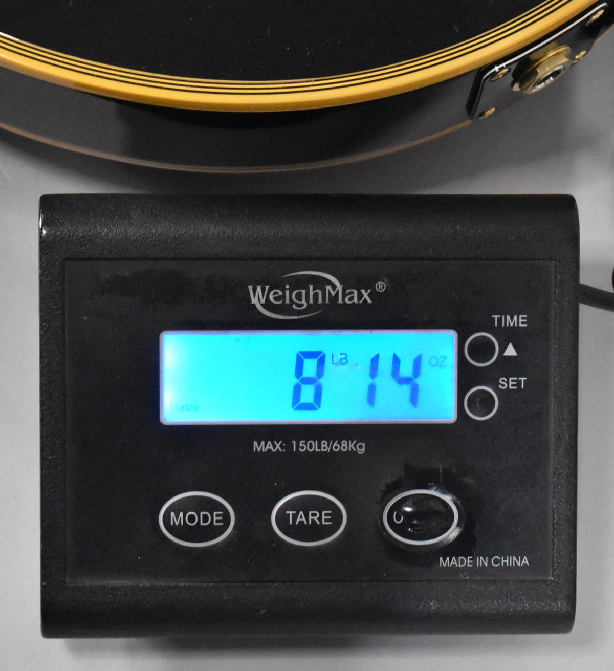 The guitar's lower bout, with cream binding and a gold strap button, rests on a digital scale displaying "8 LB 14 OZ".