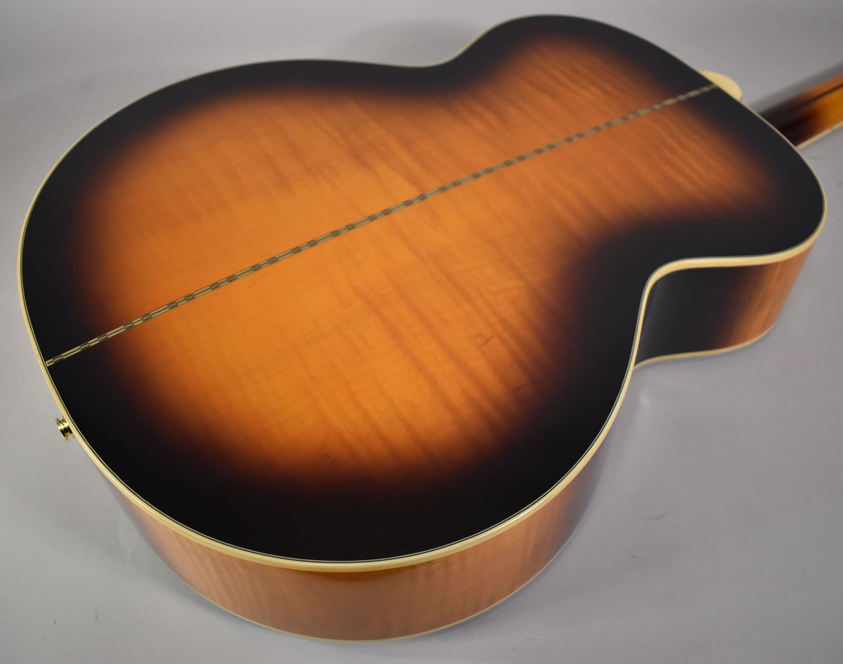The guitar's aged vintage sunburst back, with a visible wood grain and center seam, is shown at an angle, revealing the side.