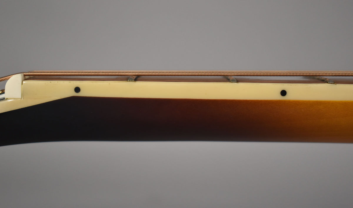 Close-up of the guitar's side, showing the aged cream binding, dark sunburst finish, and two black side dot markers.