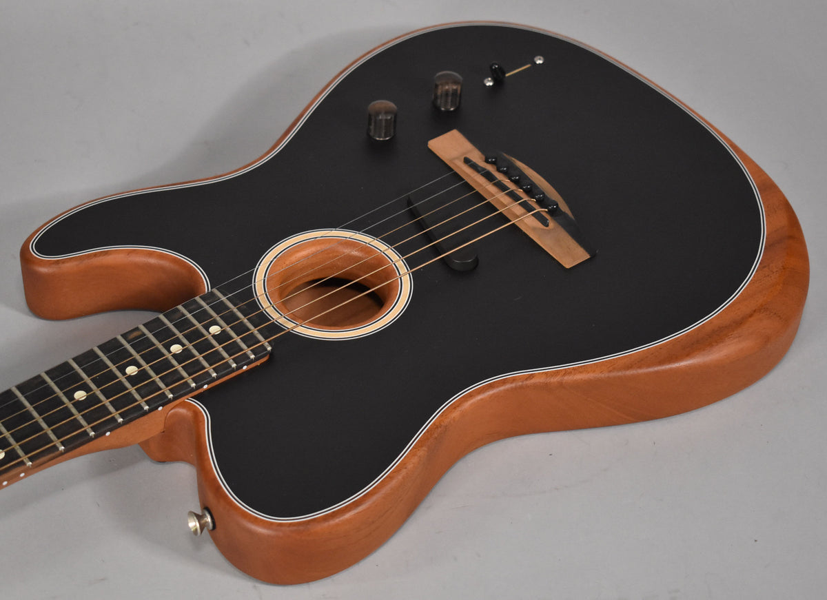 Overhead view of a black matte acoustic guitar with light brown wood sides, a soundhole, bridge, and three control knobs.
