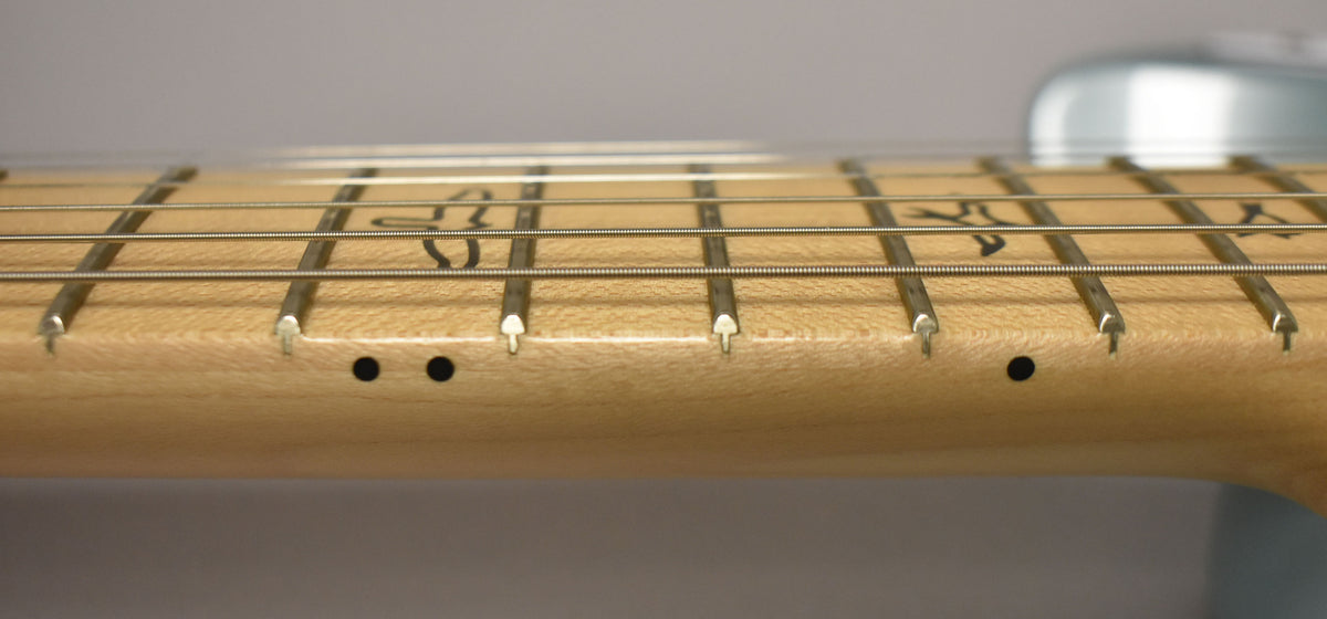 Close-up of the light-colored maple fretboard and frets, with black dot markers on the side and bird inlays on the top.