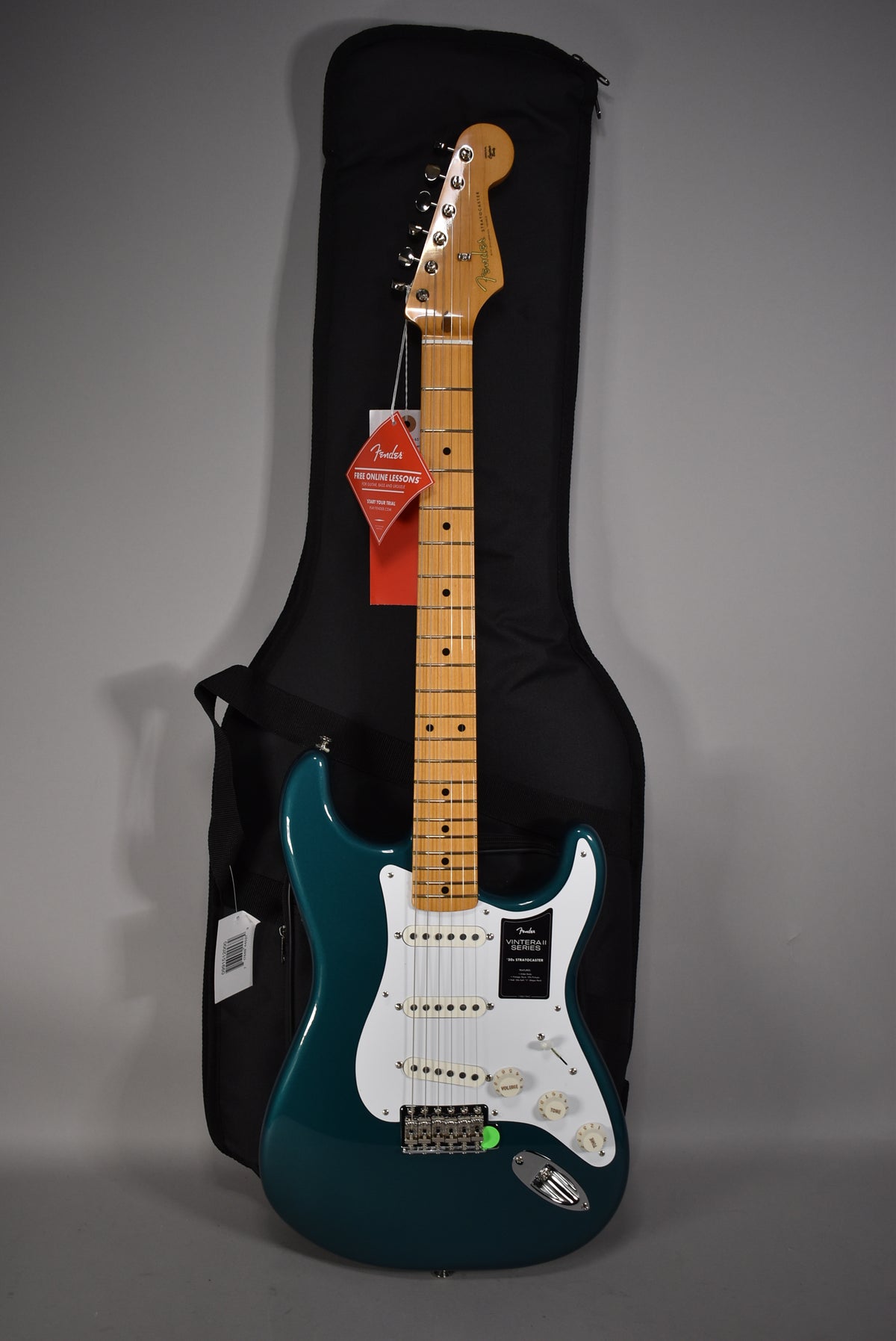 Full-length view of a glossy Ocean Turquoise Stratocaster with a white pickguard, three single-coil pickups, and a maple neck.