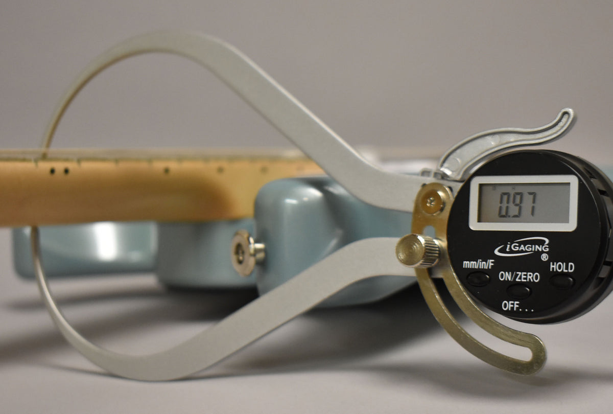 A digital caliper measures the neck relief of the Polar Blue guitar, showing 0.97mm on its display.