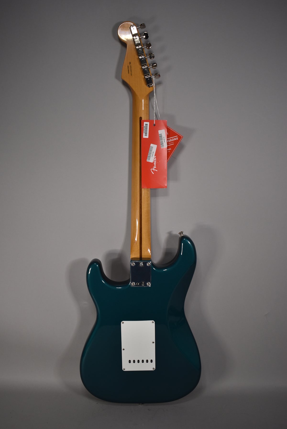 Full rear view of an Ocean Turquoise Stratocaster, showing the glossy finish, maple neck, and white tremolo cover.