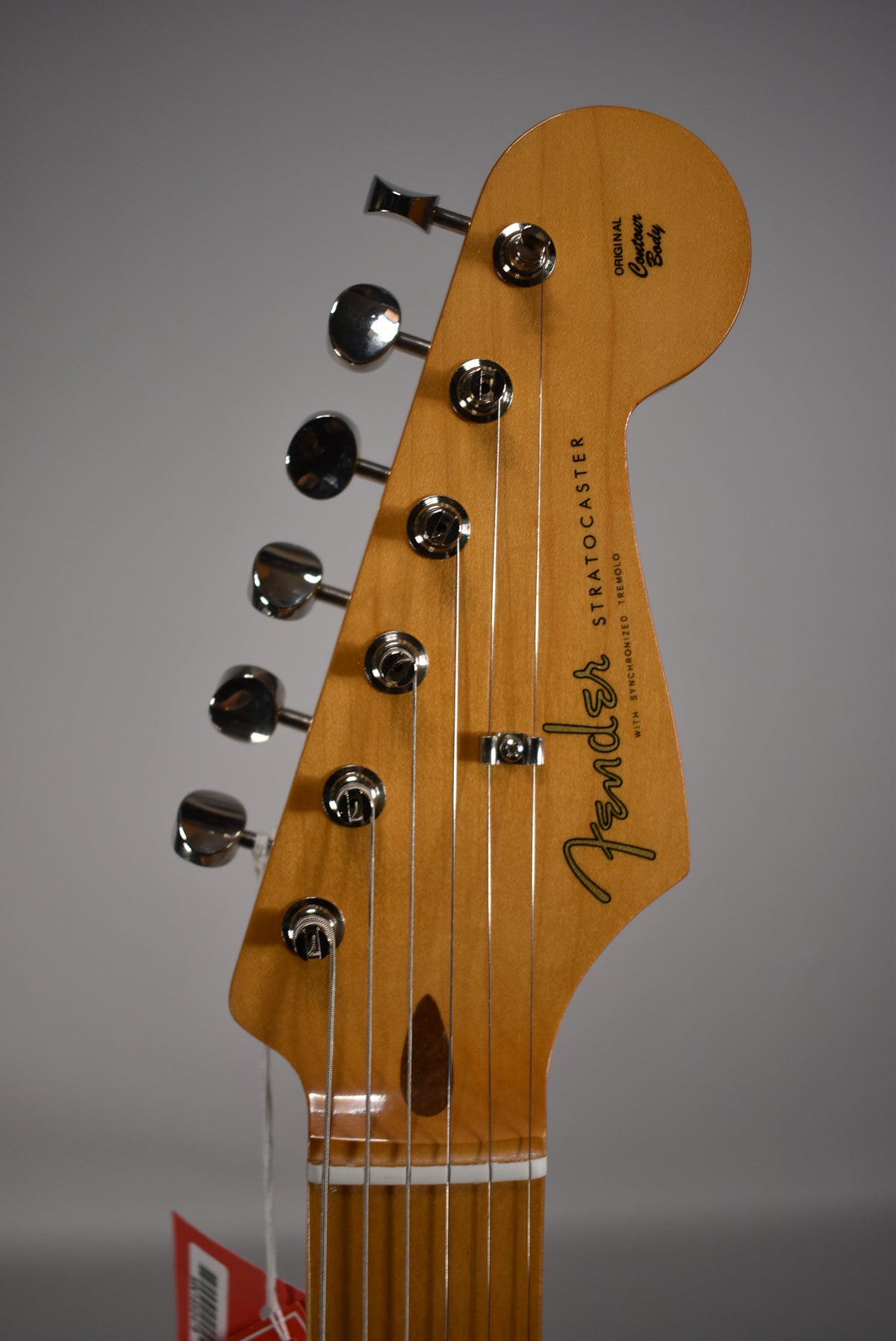 The guitar's headstock, with a light wood finish and six chrome tuners, is angled slightly left, showing the string tree.