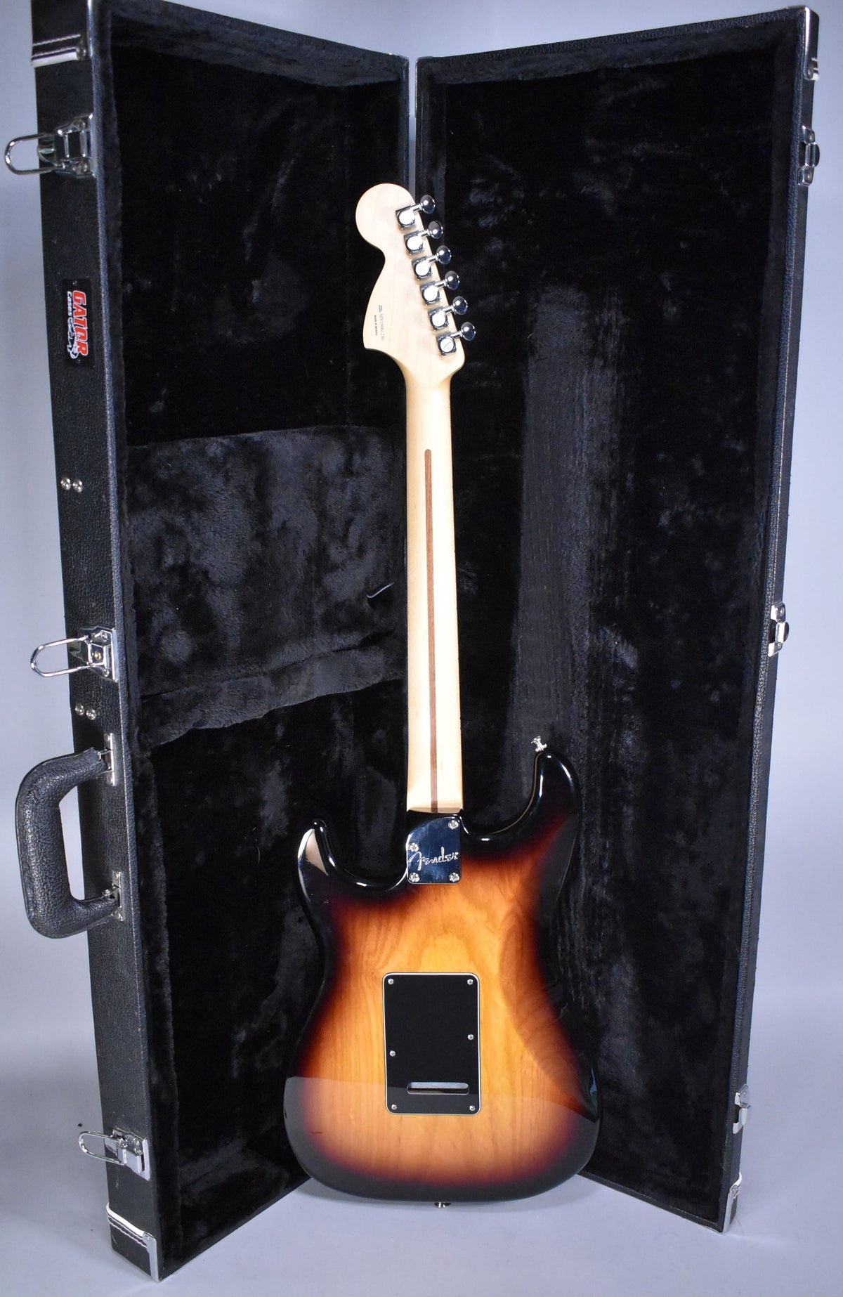 Full rear view of a glossy 3-tone sunburst Stratocaster with a maple neck, chrome tuners, and a black tremolo cover.