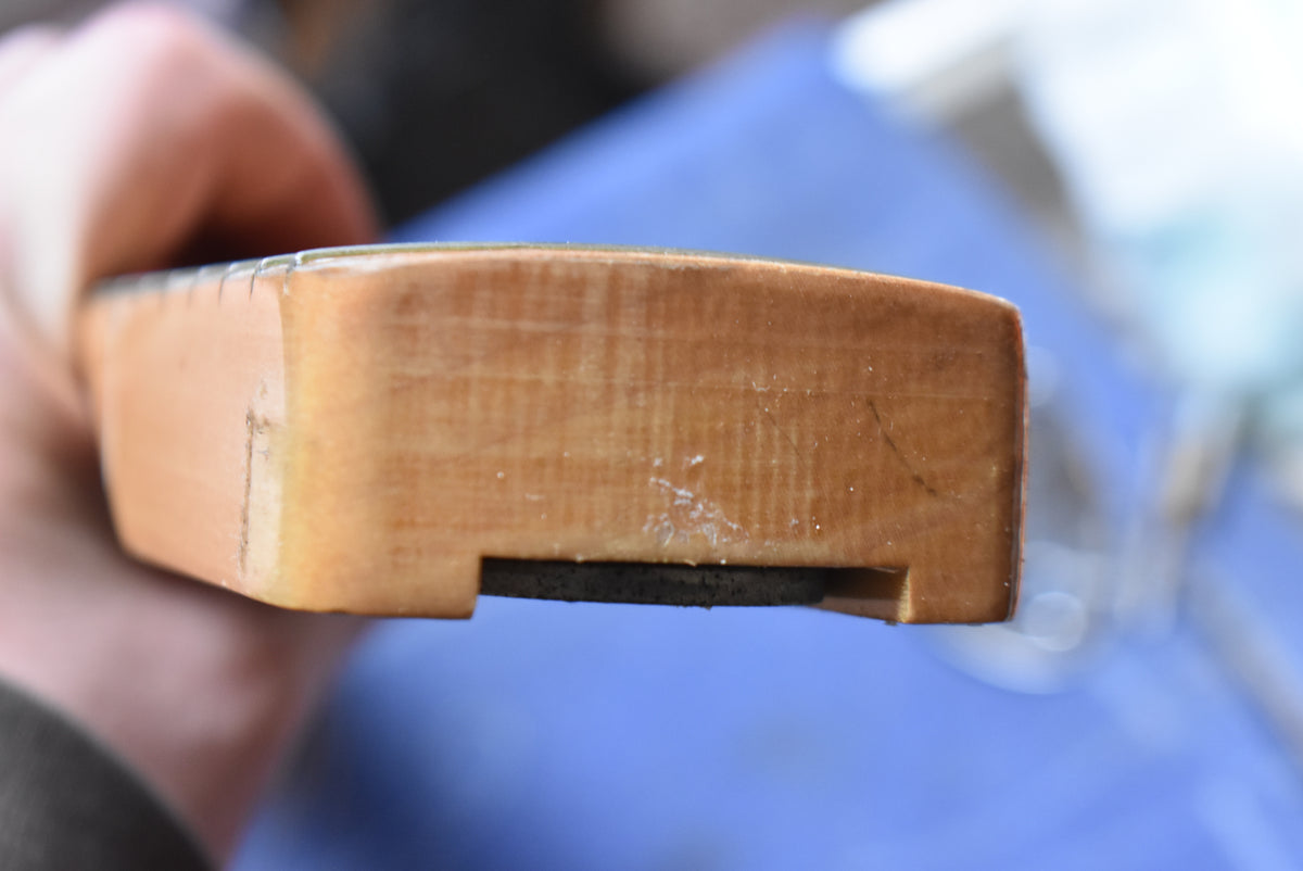 Close-up of the natural finish maple neck heel, showing some finish wear and a dark, rectangular truss rod adjustment slot.