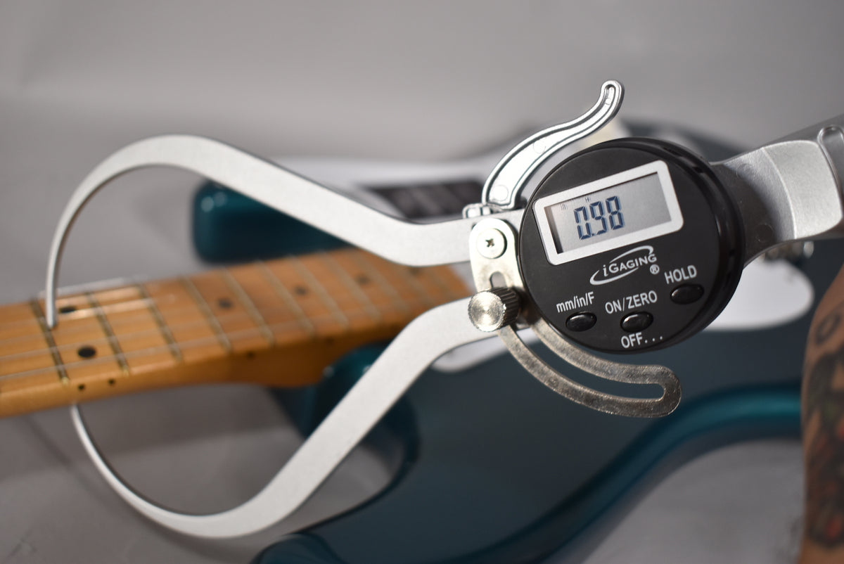 A digital caliper measures the fret height at 0.98mm on the maple fretboard of the Ocean Turquoise Stratocaster.