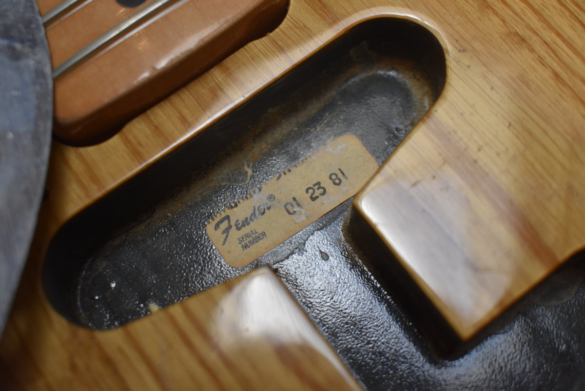 Close-up of the neck pocket, showing a worn serial number sticker and the natural wood grain of the body.