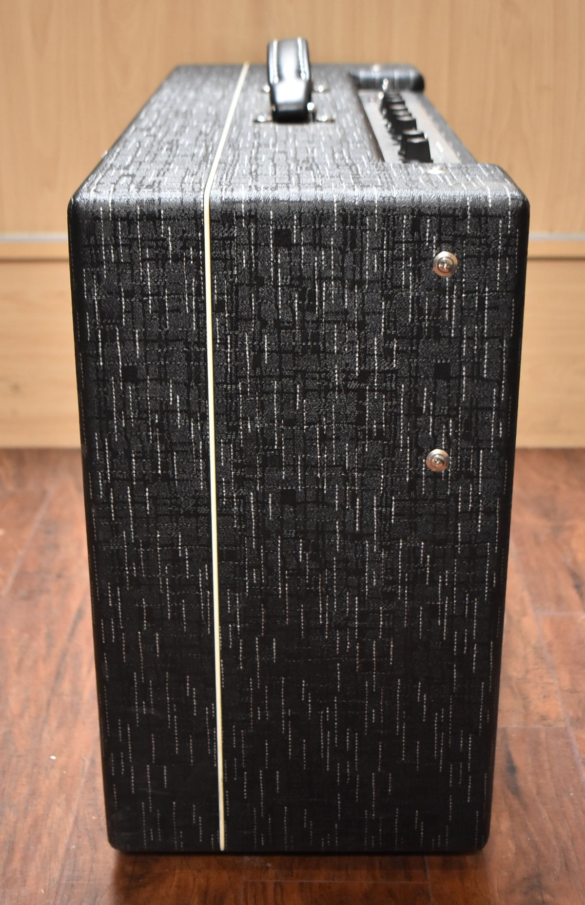 The amp's right side and top are visible, showing black textured tolex with white piping, a black handle, and top-mounted controls.