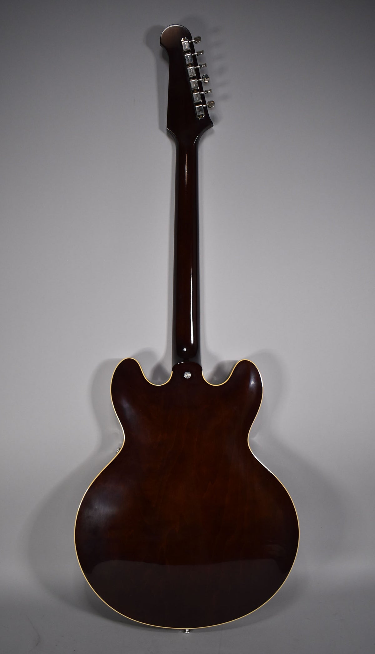 The guitar's back, neck, and headstock are visible, all in a dark walnut finish with subtle checking and cream binding.